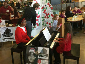 two students playing pianos at a concert christmas fundraising event