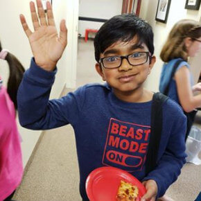 one of our students smiling and waving at the camera