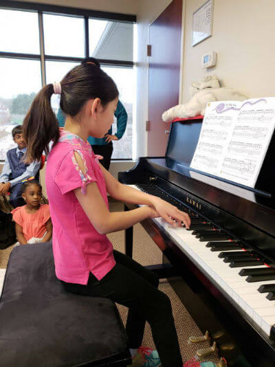 One of our students playing piano and reading sheet music in class