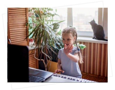 girl waving to her piano teacher on a laptop
